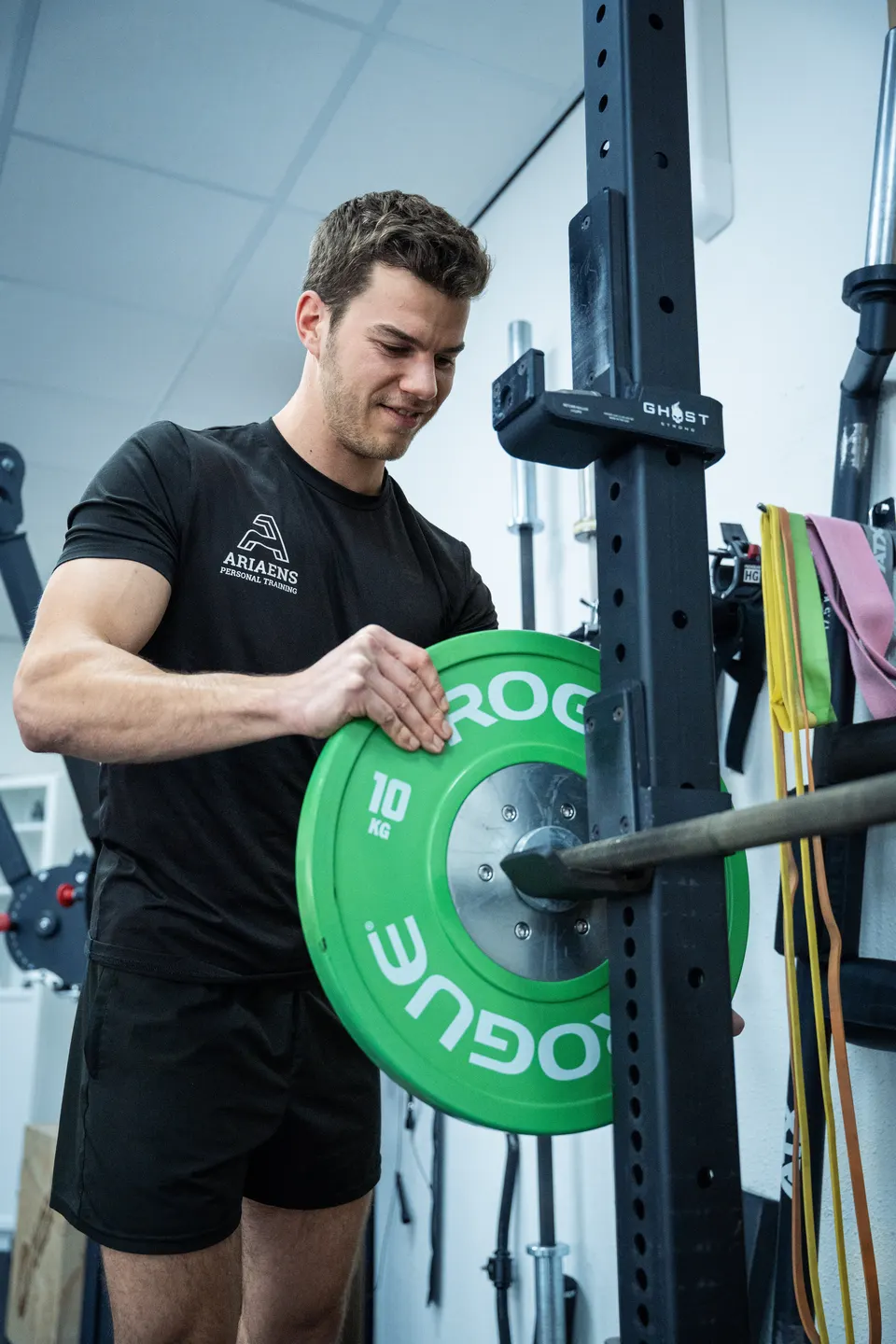 Trainer van Arieans Personal Training verwisselt een halterschijf