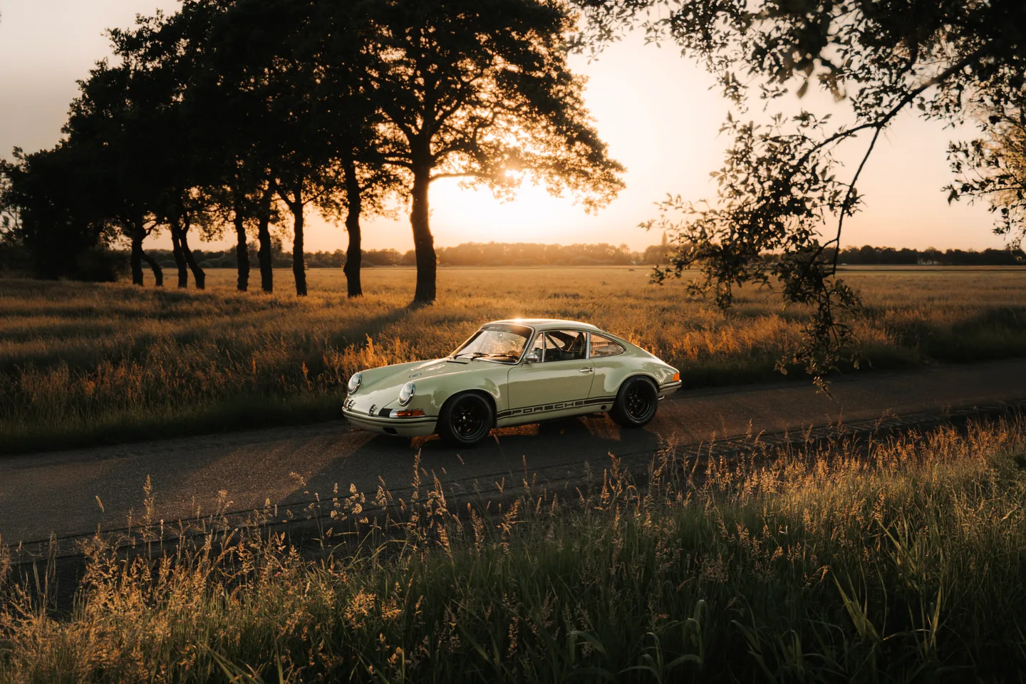 Klassieke sportwagen in een veld tijdens zonsondergang