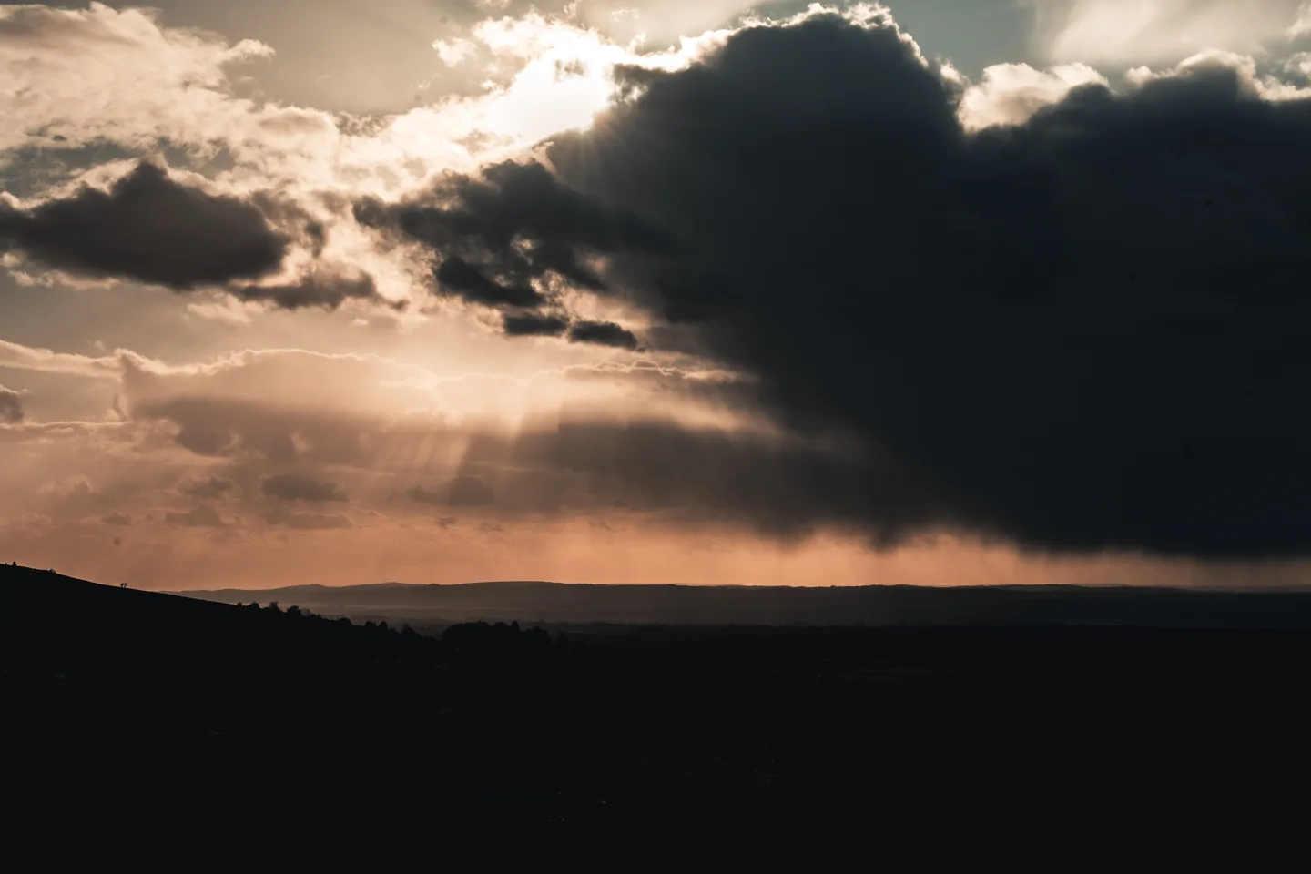 Zonnestralen boven een heuvelachtig landschap