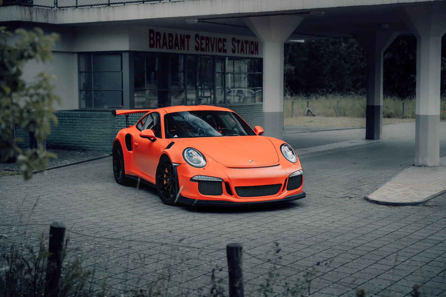 Oranje Porsche bij een verlaten tankstation
