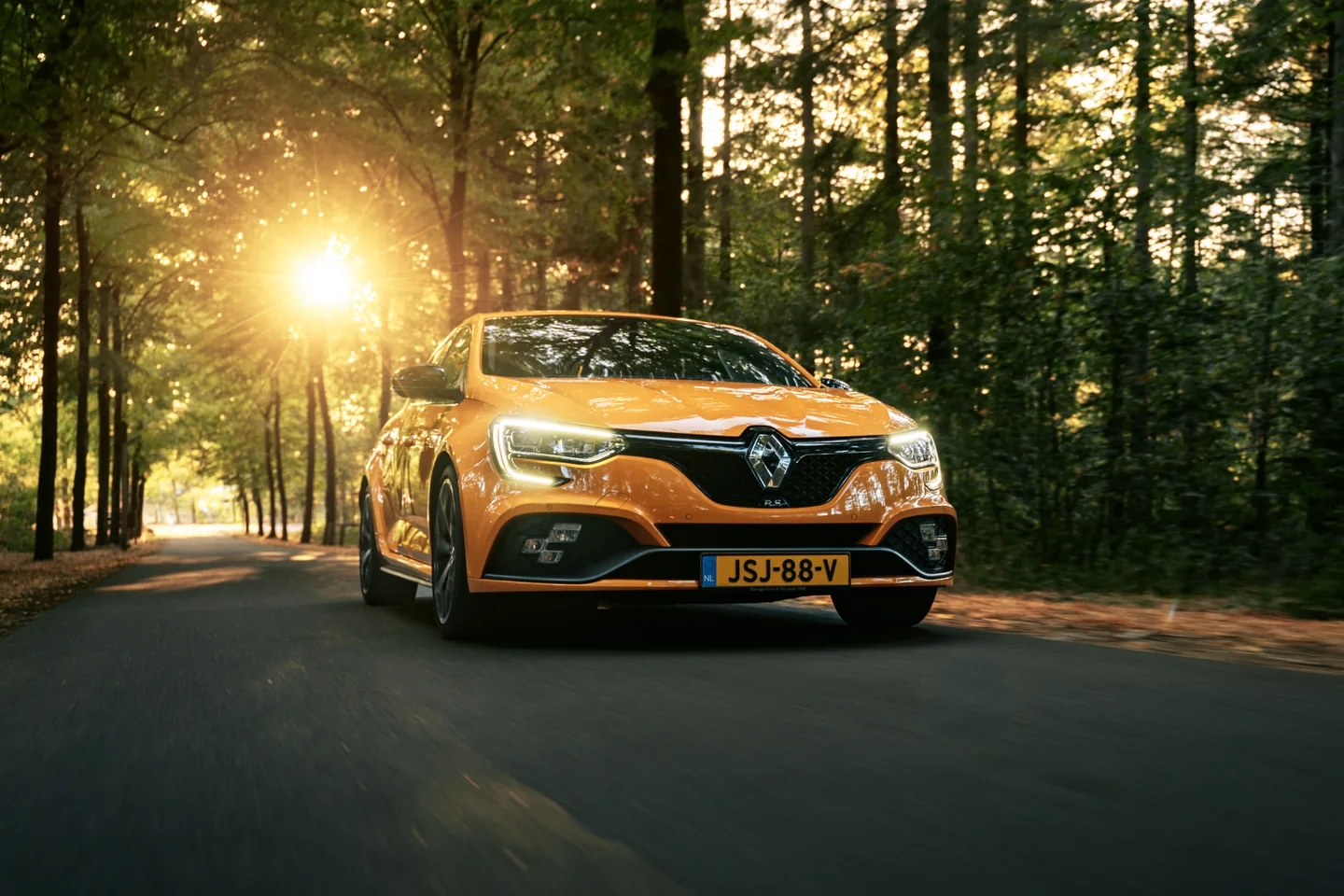 Oranje Renault gefotografeerd in beweging tussen bomen
